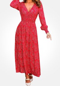 Vestido maxi floral rojo con un profundo escote en V, mangas largas abullonadas y una cintura ajustada. Presenta una falda fluida y delicados patrones blancos.
