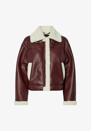 Tamsiai raudonas oda trumpas švarkas su grietinėlės spalvos avikailio pamušalu, plačiu apykakle ir priekinėmis kišenėmis. Yra dirželiai ir sagtis ant peties.