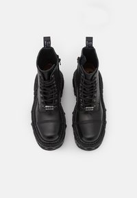 Svarta läderankelstövlar med snörning, sidoglasyr, texturerad sömnad och kontrasterande sula med en kraftig profil.