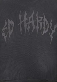 Sudadera negra con texto en negrita y dentado "ED HARDY" en un tono de negro ligeramente más claro. Confeccionada en tela texturizada y con puños de canalé.
