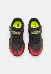 Sorte og røde sneakers med en tekstureret overdel, prydet med neongule detaljer og en Velcro-rem. Designet til fleksibilitet og komfort.