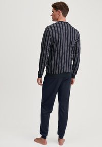 Zwart gestreepte lange mouw top met veelkleurige verticale lijnen, gecombineerd met marineblauwe sweatpants. Zachte stof, ribgebreide manchetten en tailleband.