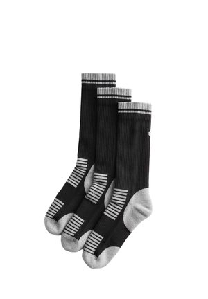 Tre sorte sportsstrømper med grå hæle, tæer og stribede detaljer stablet mod en hvid baggrund.