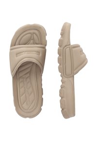 Beige slip-on sandals made of rubber, featuring a wide strap with raised branding, textured footbed, and a treaded sole for grip.