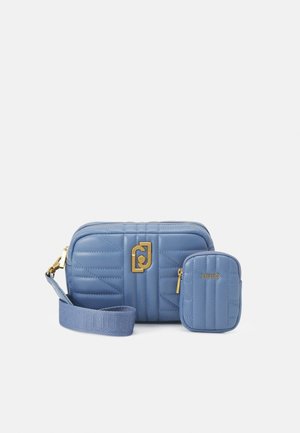 Deux sacs matelassés bleu clair côte à côte : un grand sac bandoulière avec fermoir doré et une petite pochette avec fermeture éclair et logo.
