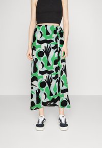 Maxi rok in groen met zwarte abstracte patronen. Gemaakt van lichte stof, met een striksluiting in de taille en een vloeiende silhouet.