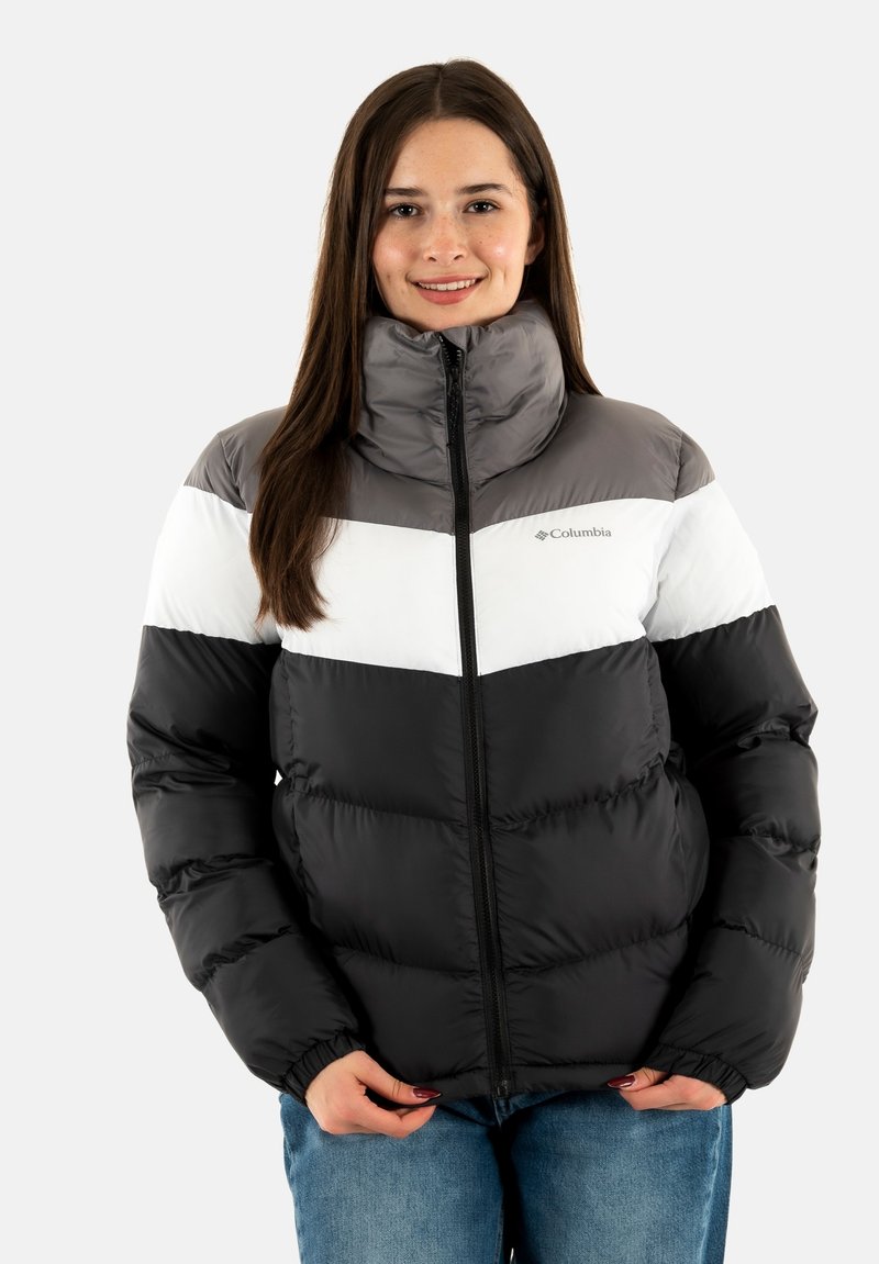 Giacca imbottita nera, grigia e bianca con colletto alto e chiusura zip. Presenta un design a Chevron e polsini elastici. Materiale leggero e isolante.