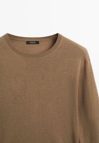 Brązowy sweter dzianinowy z okrągłym dekoltem i żeberkową strukturą. Metka mówi "Massimo Dutti", co wskazuje na pochodzenie marki z Chin.