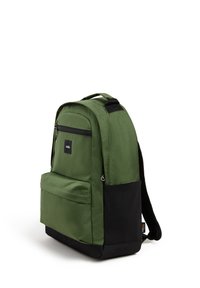 Mochila de tela verde con superficie texturizada, que cuenta con un bolsillo frontal, base negra y correas ajustables. Cierre con cremallera y detalle de logo.