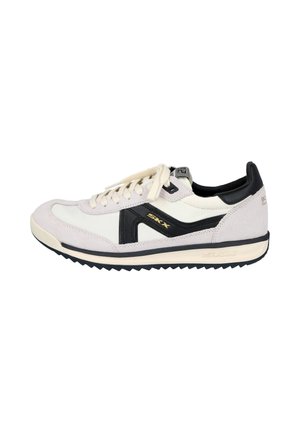 Zapatilla blanca y gris claro con detalles en negro, suela negra con dibujo en zigzag, cierre de cordones y marca "SKX" en el lateral y el talón.