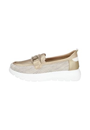Zapatilla estilo mocasín beige con parte superior texturizada, hebilla decorativa, suela blanca gruesa y laterales de tejido de malla.
