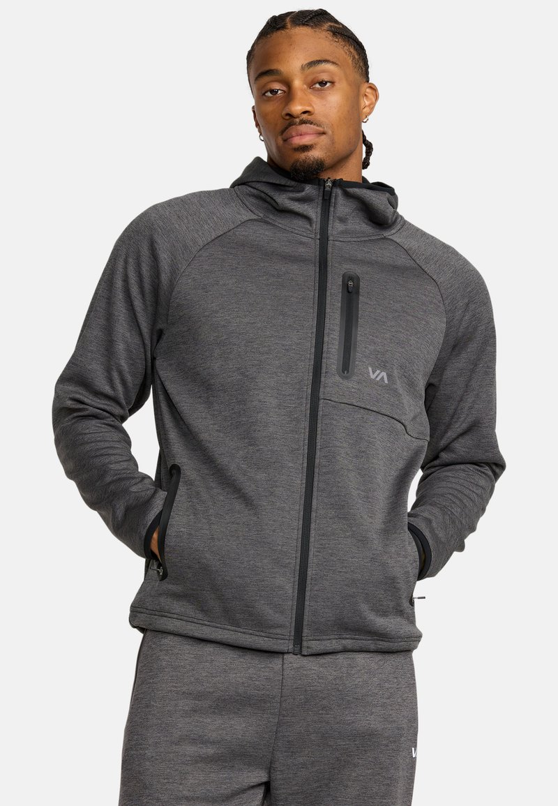 Veste à capuche zippée gris foncé en tissu texturé, avec une poche poitrine et des accents noirs sur la fermeture éclair et les poignets.