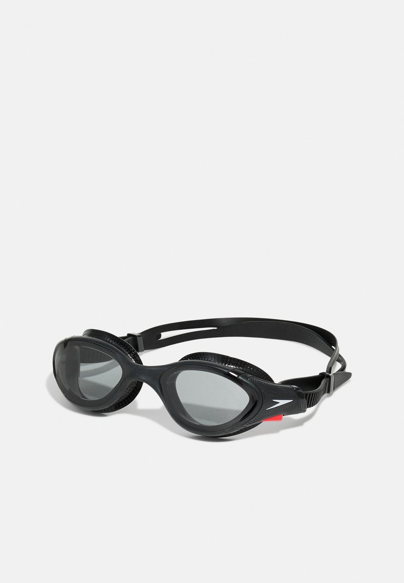 Lunettes de natation noires avec lentilles grises, design épuré, joints en caoutchouc souple, sangle réglable et accent logo sur le côté.