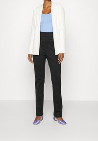 Bílý blejzr přes světle modrý tílko, doplněný černými kalhotami a levandulovými lodičkami. Látky jsou hladké s formálním designem.