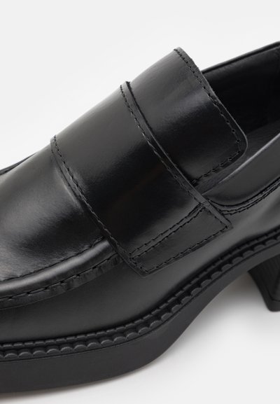 Svarta läder slip-on skor med en slät finish, med dubbla remmar, kontrasterande sömmar och en tjock, texturerad sula.