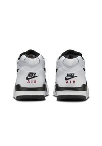 Baskets en cuir blanc avec un accent noir, un talon texturé et un logo "AIR" rouge à l'arrière. Design épuré avec un col rembourré.