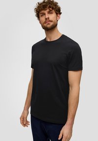 Camiseta de algodón negra con cuello redondo clásico y mangas cortas, textura suave y un diseño simple y sin adornos.