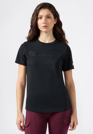 T-shirt in cotone nero con maniche corte e scollatura rotonda. La parte anteriore presenta il logo "Champion" ricamato in rilievo di un nero coordinato.
