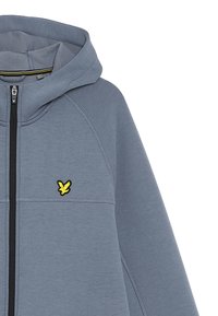 Grijze zip-up hoodie met capuchon, voorzien van zwarte accenten en een klein geel logo op de borst, gemaakt van een zachte, gestructureerde stof.