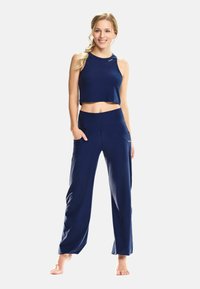 Navy blue crop top and wide-leg pants made of soft fabric. Top features a rounded neckline, while pants have diagonal pockets and a relaxed fit.