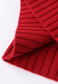 Red knitted fabric with vertical ribbed texture, featuring a soft, fluffy finish. Edges are neatly folded, showcasing the material's thickness.