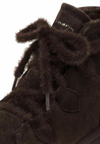 Hnědé semišové kotníkové boty s texturovanými tkaničkami a měkkými kožíškovými akcenty, vybavené polstrovaným límcem a kontrastní gumovou podrážkou.