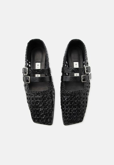 Μαύρα πλεκτά δερμάτινα παπούτσια μπαλαρίνες με τετράγωνα μύτα και διπλές αγκράφες, σε λευκό φόντο, από πάνω.