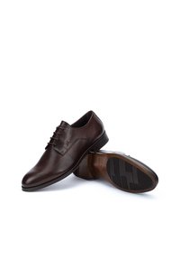 Zapatos de vestir de cuero marrón con una textura suave, diseño de cordones, forma estructurada y suela de goma con un patrón de dibujo geométrico.