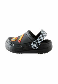 Black slip-on shoe with fuzzy interior, featuring colorful flame and wheel embellishments; textured rubber outsole and checkered strap.