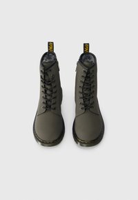 Bocanci gri închis cu un finisaj neted, vârf rotund, șireturi în față și căptușeală din blană. Prezintă o buclă branduită galbenă în spate și talpă neagră.