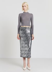 Graues, geripptes Strick-Crop-Top mit langen Ärmeln, kombiniert mit einem silbernen, glitzernden Bleistiftrock, ergänzt durch beigefarbene High Heels.