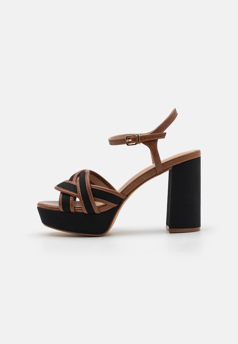 Melni platformas sandales ar blokveida papēdi, ar krustveida brūnajām siksnām un sprādzi ap potīti. Tekstūrēts audums uz papēža un zoles.