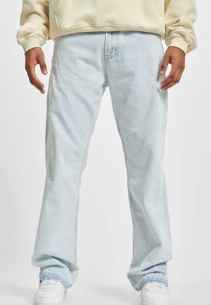 Lyse blå denimjeans med en avslappet passform, rette ben og subtil fading. Kombinert med hvite sneakers for kontrast.