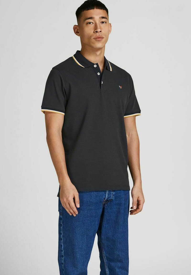 Short-sleeve polo shirt in dark gray with contrasting yellow and white stripes on the collar and sleeves. Features a small emblem on the chest.