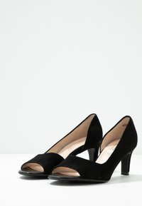 Chaussures à talons hauts en daim noir avec une conception à bout ouvert, un avant pointu et un talon effilé, avec une doublure intérieure lisse.