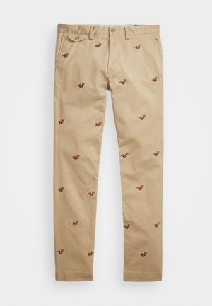 Beige chino-bukser med små broderede hest og rytter motiver spredt over stoffet, med bæltestropper og knaplukning.