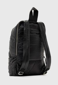 Zaino nero imbottito con esterno trapuntato, chiusura a doppia zip e spallacci regolabili. Include una maniglia superiore per il trasporto e una tasca laterale.