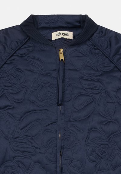 Marinblå quilted bomberjakke med blomsterbroderi, ribbet krage og glidelås i gull, som viser et glatt teksturert stoff.