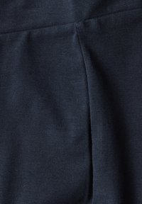 Mörkblått tyg med en jämn, elastisk textur och vertikala ribbor. Inkluderar sidoflikar för ökad rörlighet.