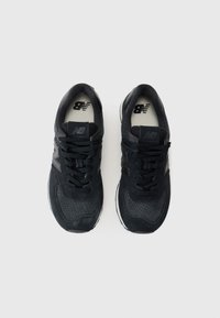 Czarne sportowe buty z teksturowaną cholewką wykonaną z siateczki i zamszu, okrągłym noskiem, sznurowanym zapięciem oraz białą podeszwą.