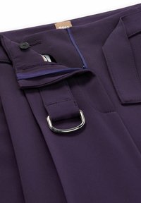 Fialové kalhoty s zipem a uzávěrem na háček, doplněné kovovým D-kroužkem. Hladká tkanina a propracované designové detaily.