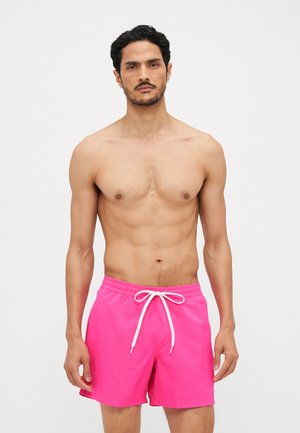 Pink swim shorts made of lightweight material with a white drawstring. Features a simple design and an elastic waistband.
