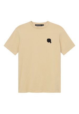 T-shirt beige à manches courtes et col rond avec un petit patch logo noir sur la poitrine gauche et une étiquette de col noire.