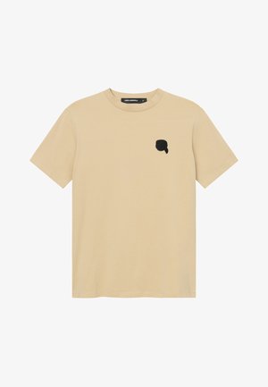 T-shirt beige à manches courtes et col rond avec un petit patch logo noir sur la poitrine gauche et une étiquette de col noire.