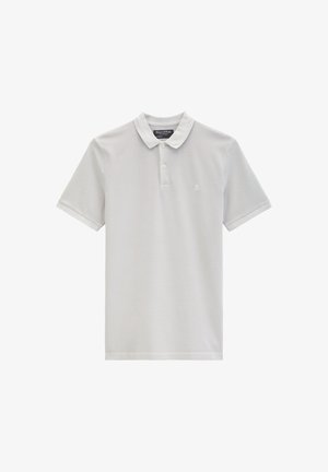 Lichtgrijs poloshirt met korte mouwen, twee knopen en een klein geborduurd logo op de linkerborst, kraag netjes opgevouwen.