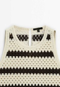 Crocheted sleeveless beige top with horizontal black stripes, round neckline, and button closure at the back.