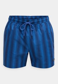 Calções de banho azuis feitos de material liso e leve, com um padrão de riscas verticais, cintura elástica com cordão e etiqueta lateral.