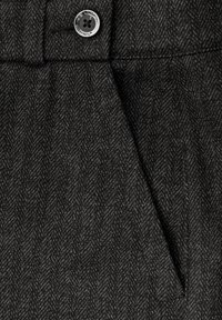 Tejido mezcla de lana en negro con un sutil patrón de espiga, que presenta un botón plateado brillante y detalles plisados cerca de la cintura.