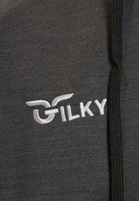 Tessuto grigio con una superficie liscia e un accento nero. Presenta il testo ricamato bianco "GILKY" e un logo con ali sul lato sinistro.