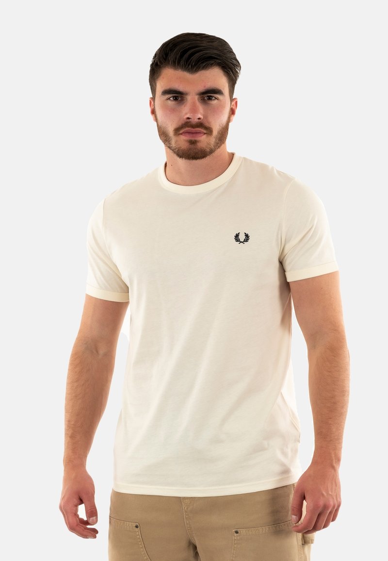 T-shirt corto a maniche corte color beige chiaro con colletto e polsini giallo pallido in contrasto, dotato di un piccolo emblema nero sul lato sinistro del petto. Materiale in cotone.